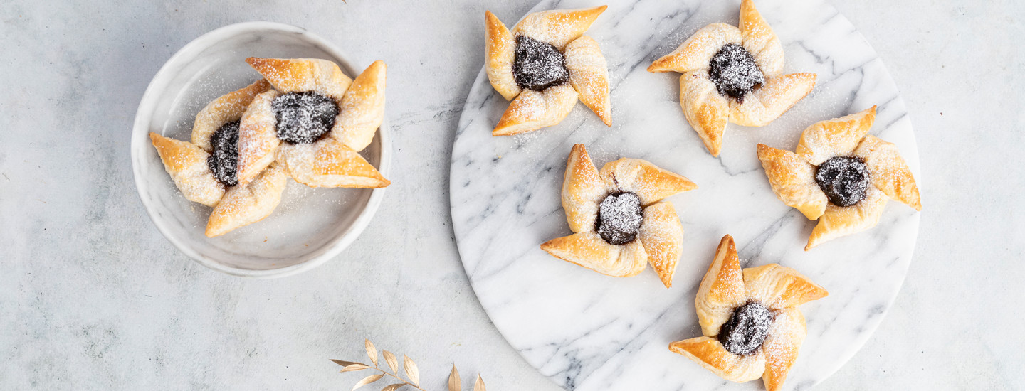 Tähtimuotoisia joulutorttuja marmorisella pyöreällä tarjottimella ja vaaleassa kulhossa. Torttujen päälle on ripoteltu tomusokeria. K-Ruoka jouluresepti.