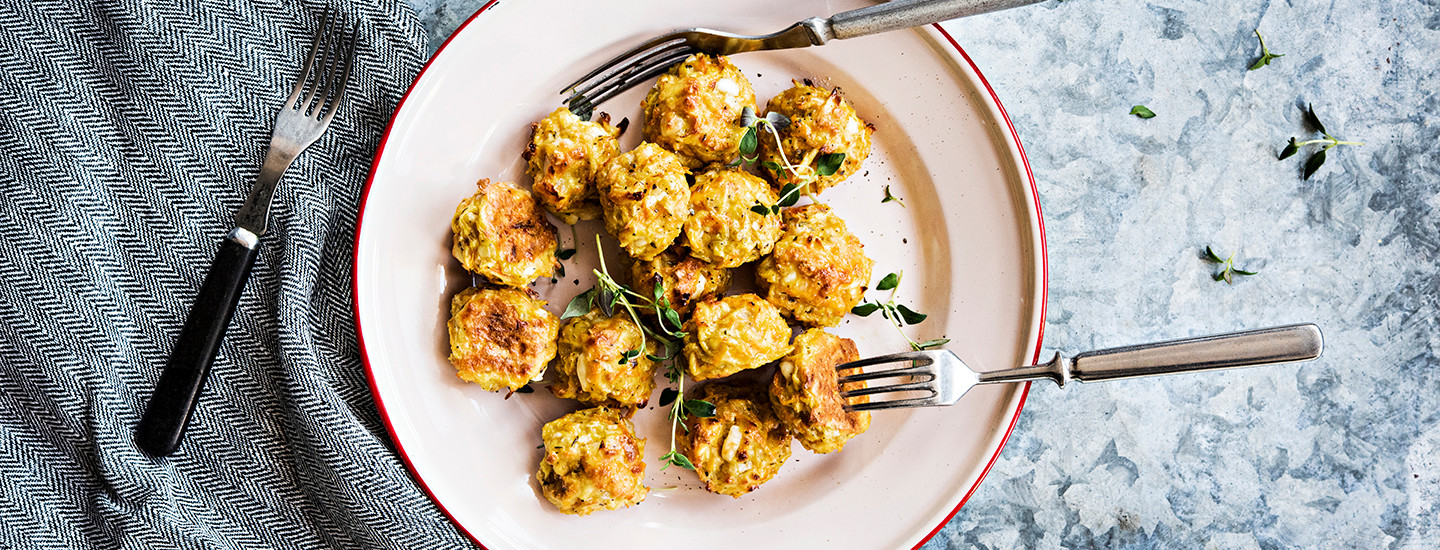 Kasvispyöryköitä valkoisella pyöreällä lautasella. Lautasella on myös kaksi haarukkaa, kolmas haarukka on lautasen vasemmalla puolella pöydällä. Pullien päälle on ripoteltu tuoreita yrttejä. K-Ruoka arkiruokaresepti.