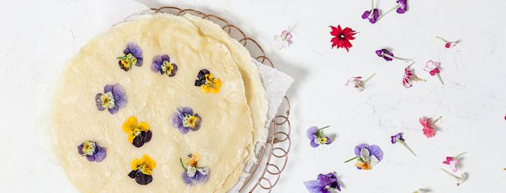 Syötäviä orvokin terälehtiä paistettujen lettujen päällä.