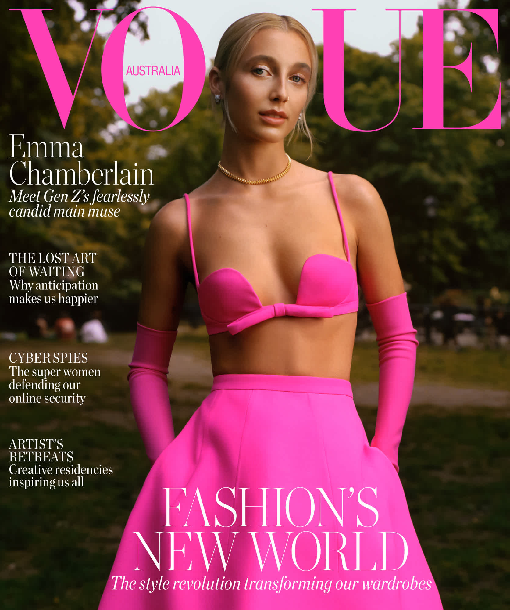 Cover of Vogue Australia with Emma Chamberlain wearing a vivid magenta look. She is wearing a bra with straps, gloves, and a skirt. She is standing in front of what looks to be a park.