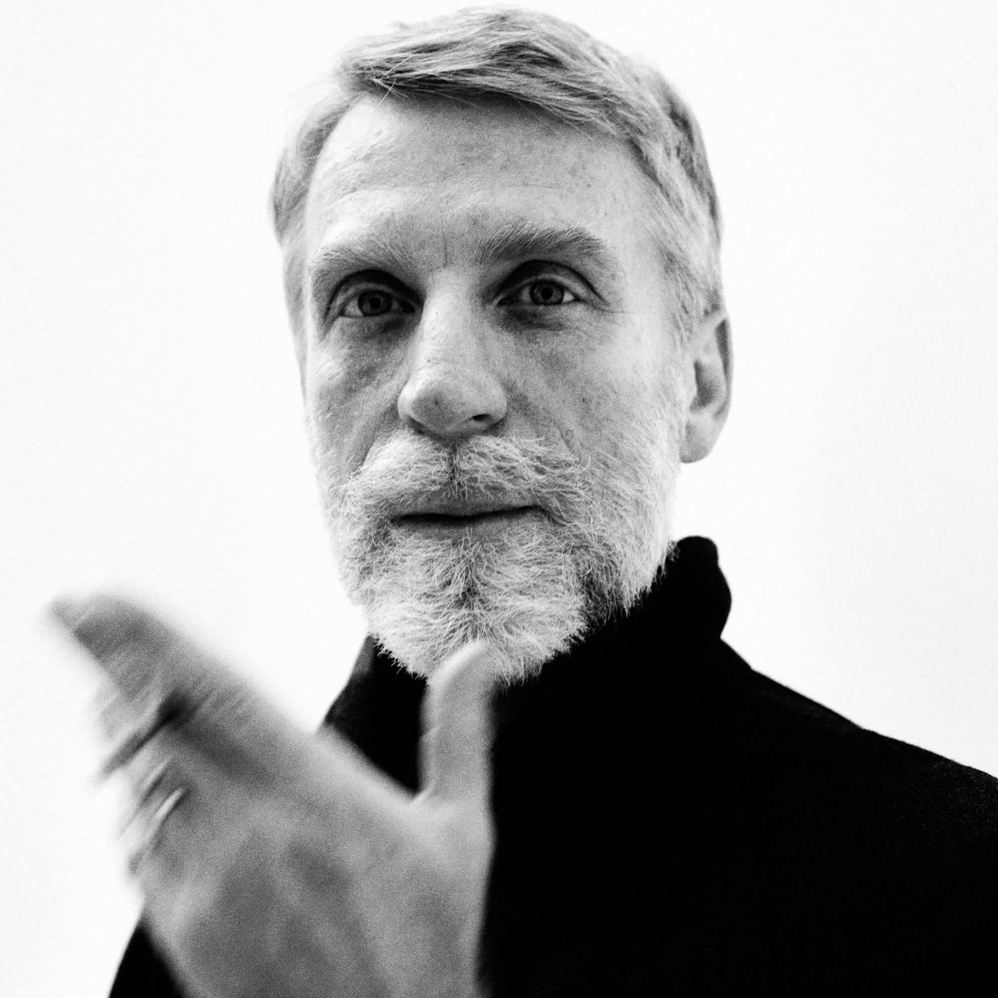 Portrait of Simone Bellotti looking at the camera with his hand gesturing in motion.