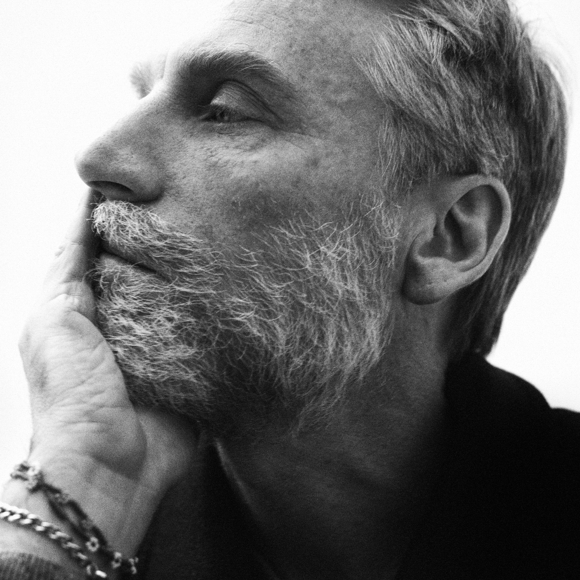 Close up portrait of Simone Bellotti looking away from the camera resting his head on his hand. 