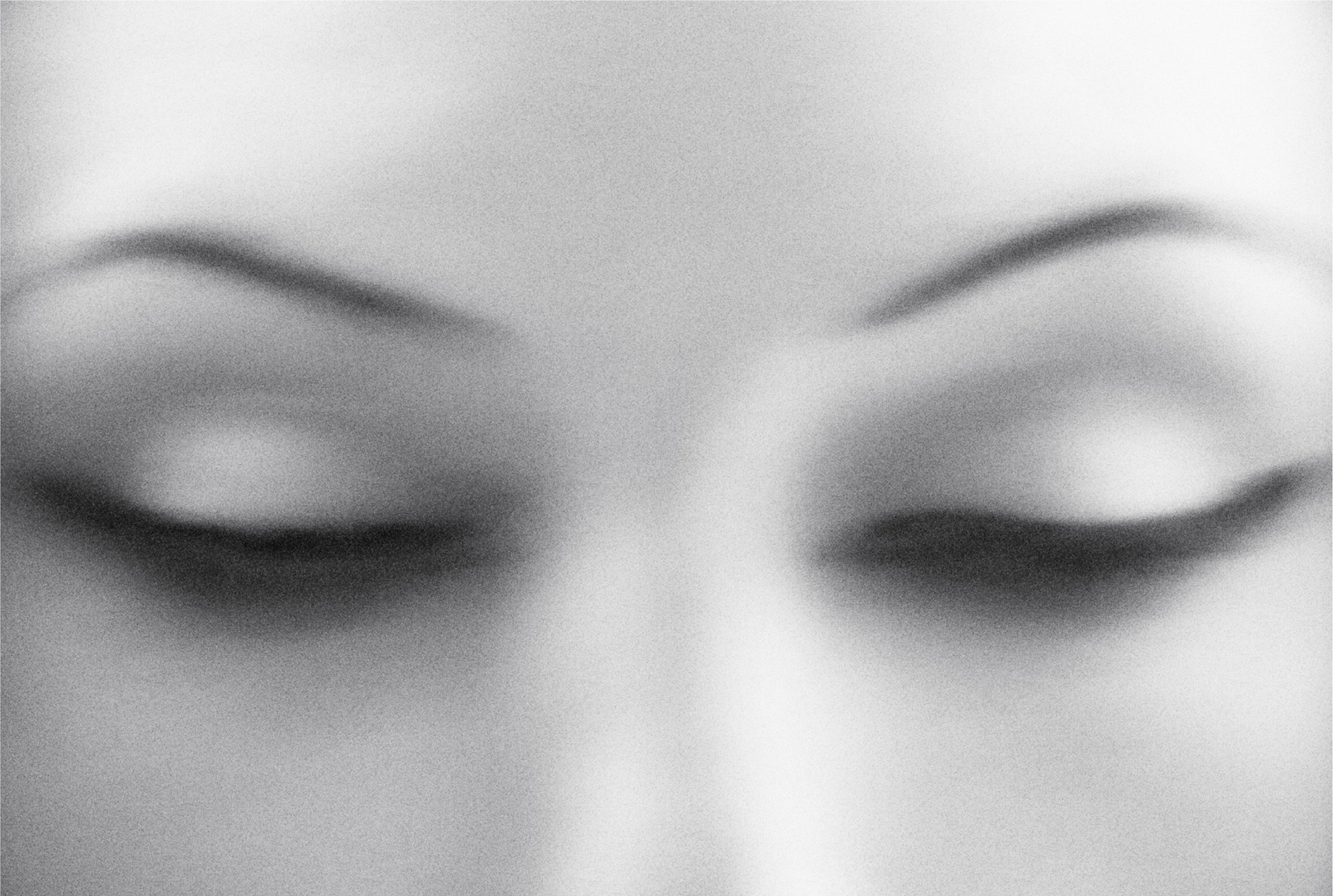 Close up image of a models eyes. The eyes are shut and there is motion blur. The model's eyes and eyebrows are centered in the frame. 