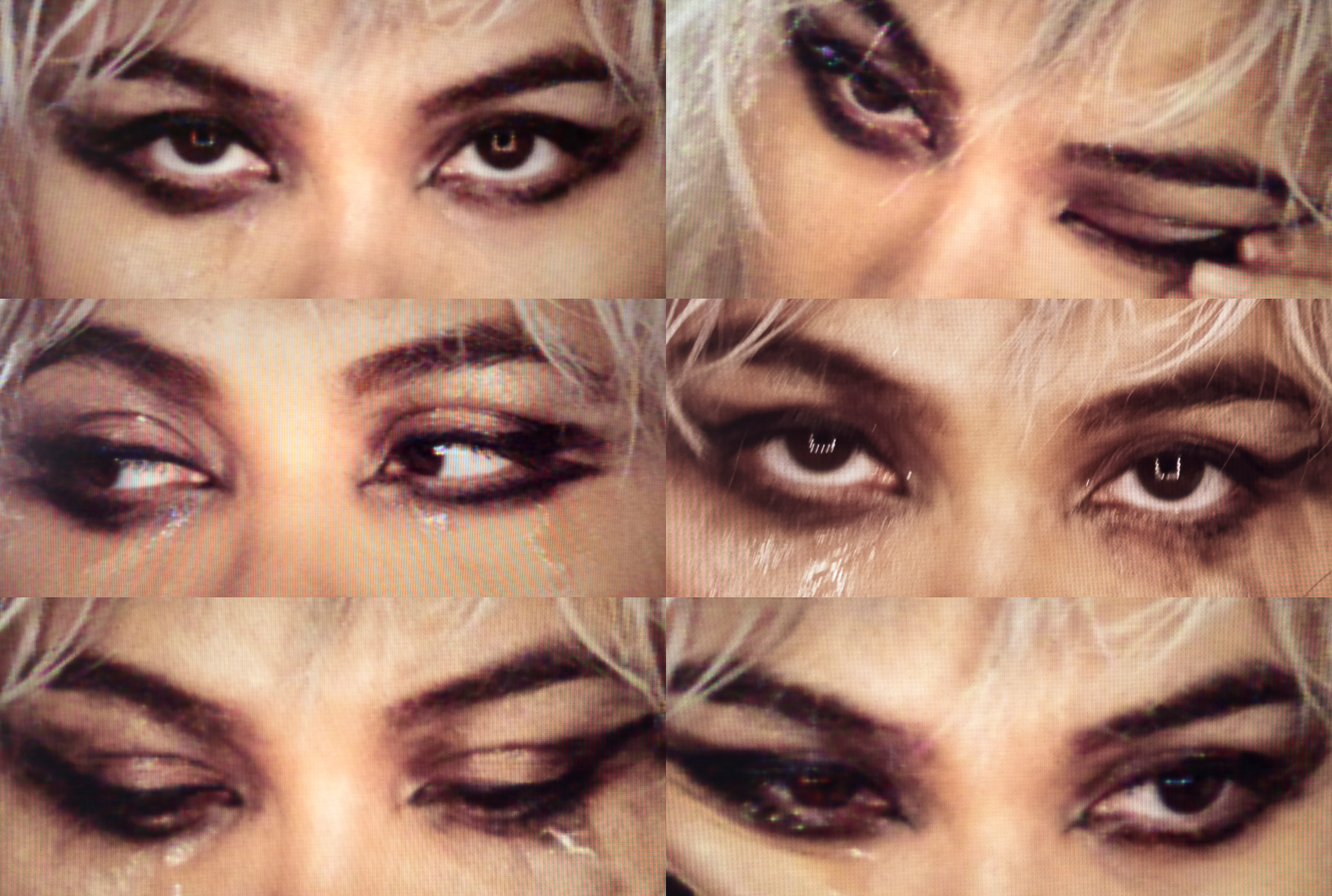 There are six different sections of the image, each has the same tight crop of a woman model's eye area. All sections have the same grungy graphic black eyeshadow look. In each section the model is moving her eyes in slightly different directions, rubbing her eyes, and pulling on the eyes. All the sections have the look of a video still. 