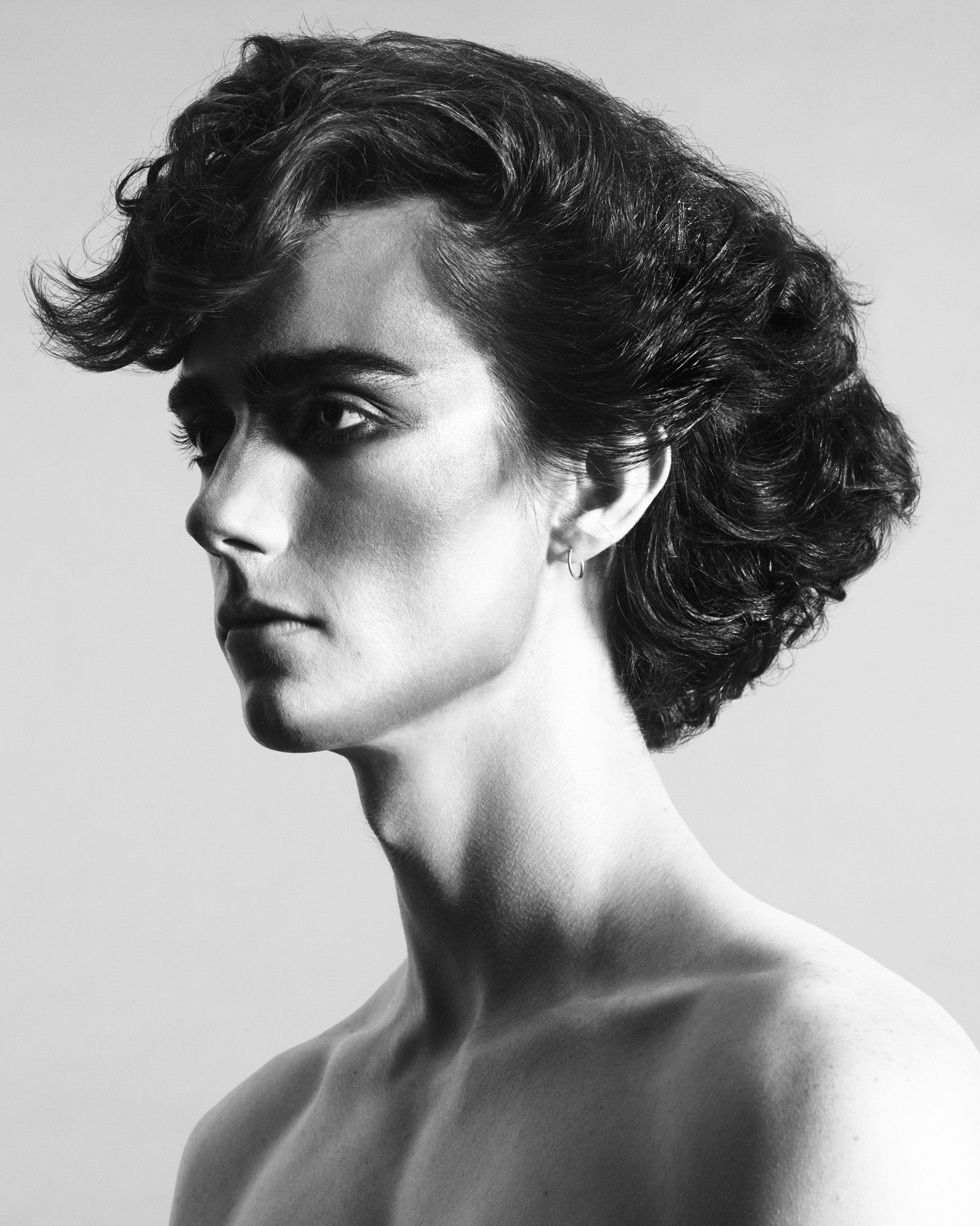 Model is depicted at a partial profile pose. Hair in the front of the model's face is swooping upwards, and the back section of the hair is styled in a dense and even block. 