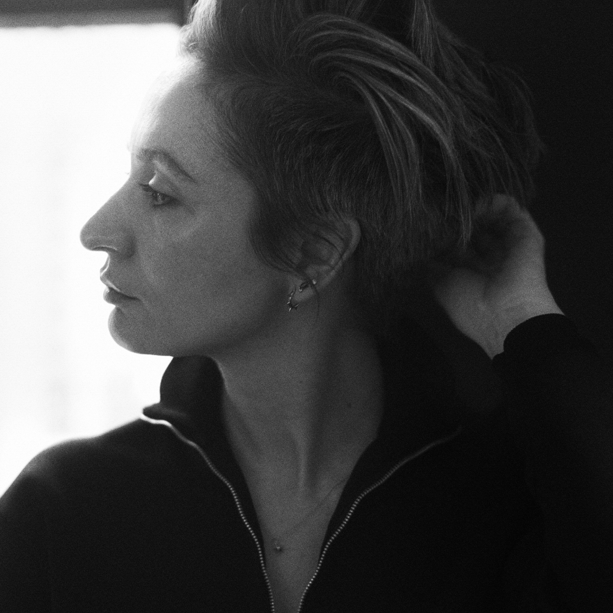 Portrait of Veronica Leoni in profile with her hand touching that back of her hair. 