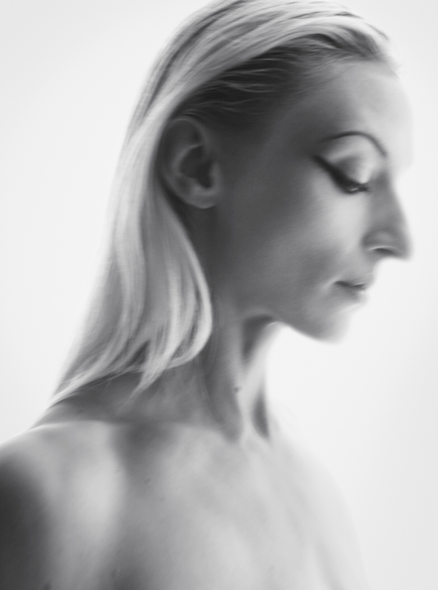 Model with blonde, slicked back hair is at a half profile pose within the frame. The background is a solid white. 