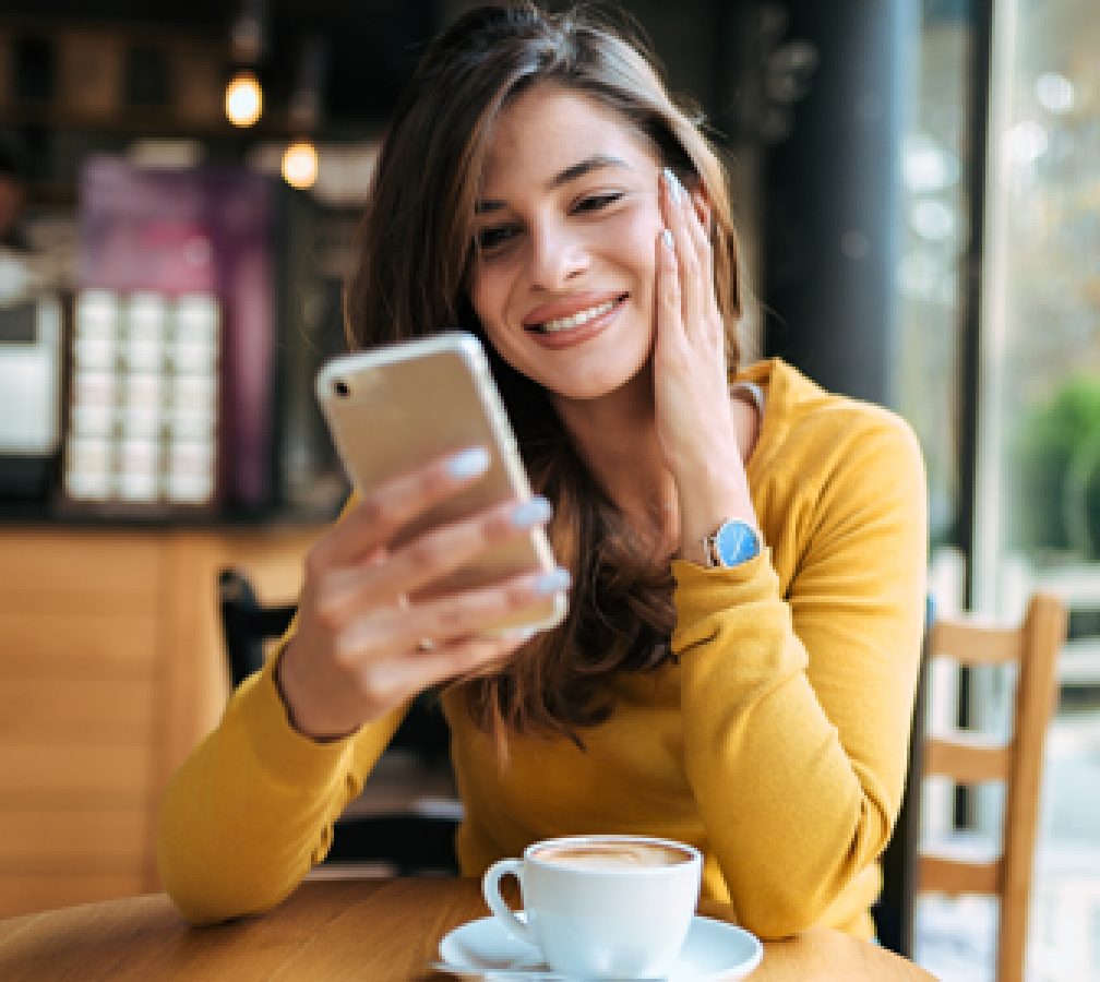 woman in coffee shop smiling at her phone