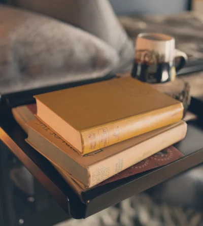A black tray accessory rests on the top bunk with three books and a coffee mug (with coaster) resting on top of it.
