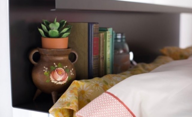 A super closeup of a decorated top bunk bookshelf on a charcoal Queen Over Queen Adult Bunk Bed.