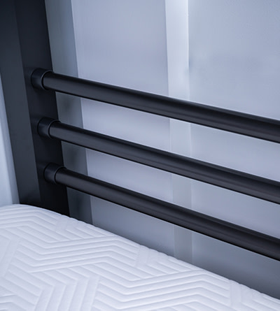 A charcoal three-post pillow support attached to the bottom bunk of a Twin XL Over Queen Adult Bunk Bed