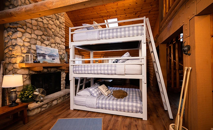 White Triple Bunk Bed for adults in an upscale rustic cabin seen from the right-hand side of the bed with the guardrails at a slight distance and slightly angled toward the lower right-hand corner.