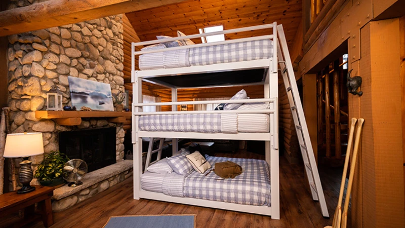 White Triple Bunk Bed for adults in an upscale rustic cabin seen from the right-hand side of the bed with the guardrails at a slight distance and slightly angled toward the lower right-hand corner.