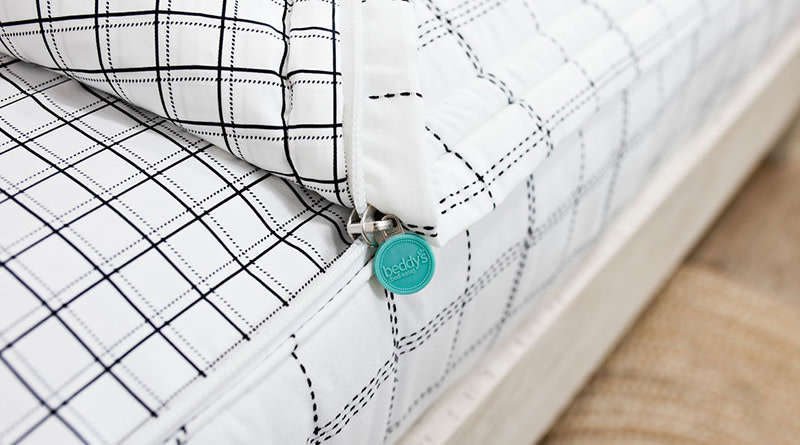 Aiden-style (off-white with grayish brown cross pattern) zipper bedding partially unzipped to reveal the bottom layer sheet and very zoomed in on the zipper.