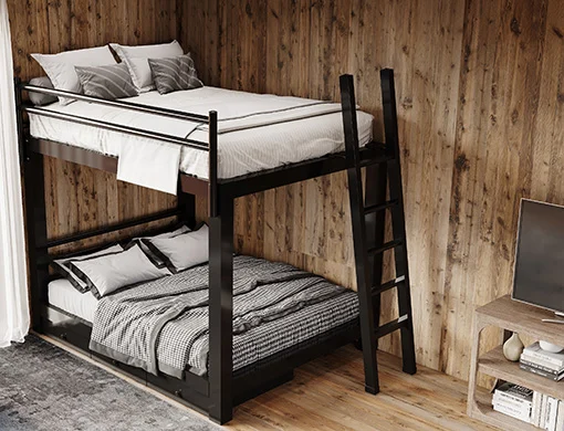 A black Queen Over Queen Adult Bunk Bed in a rustic, sparsely decorated cabin. Seen from the lower right hand corner from a high angle.