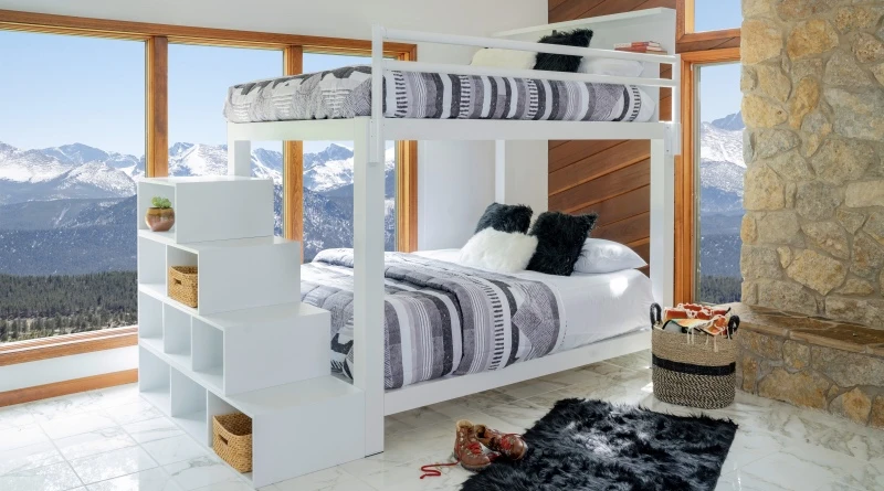 A white Queen Over Queen Adult Bunk Bed with a matching staircase accessory in a mountain cabin bedroom.