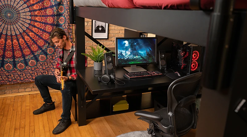 A young man playing guitars on the staircase accessory next to his black Queen Adult Loft Bed