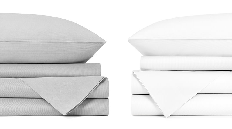 Two sets of folded up and partially visible sheets - light gray on the left and white on the right - sitting opposite one another on a white background