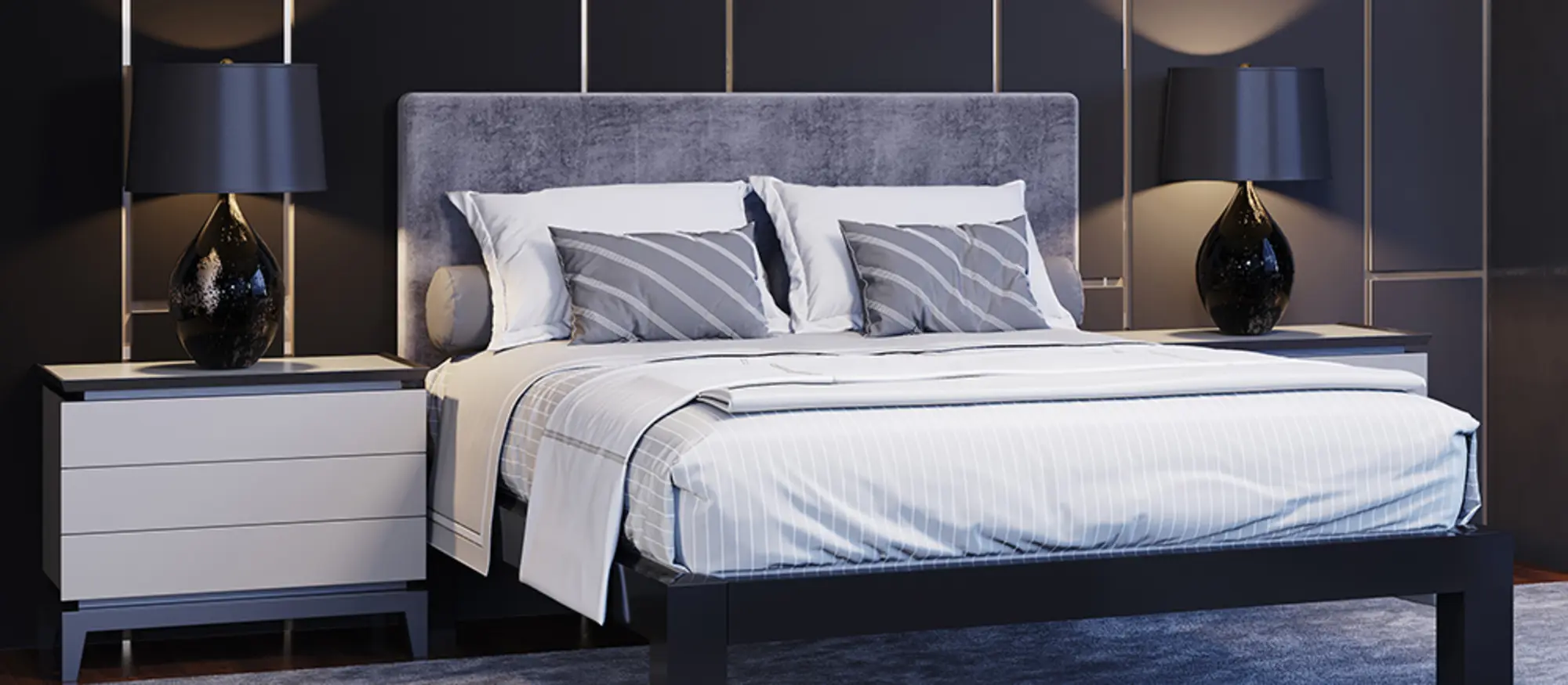 A black Queen size metal platform bed frame with a gray fabric headboard in an upscale high rise apartment with a black wall behind it and two white side tables on either side with black lamps. Seen at nighttime from a slight angle at the lower right-hand corner of the bed.