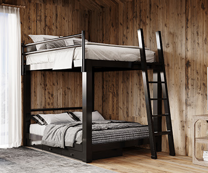 A black Queen Over Queen Adult Bunk Bed in a rustic, sparsely decorated cabin. Seen from the lower right hand corner of the bed.
