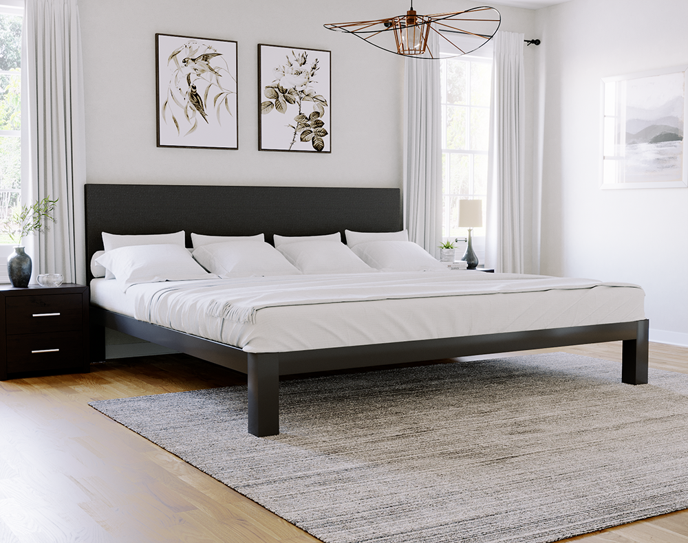 Charcoal Alaskan King size metal Platform Bed in an affluent looking but modest master bedroom with white walls. Bed has a charcoal colored foam upholstered headboard and all white bedding and pillows. Seen from the lower left-hand corner of the bed.