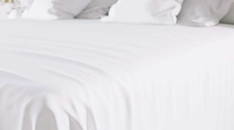 White sheets on a King size metal Platform Bed seen at an extreme close up.