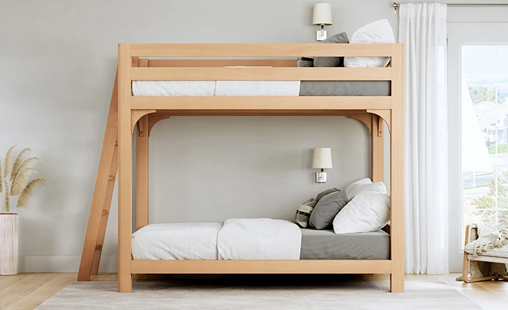 Light colored queen over queen wooden bunk bed for adults in a night, upscale guest room with a lot of natural light. Seen directly from the left-hand side of the bed.