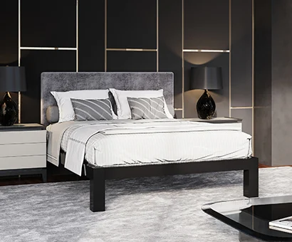 A black queen size metal Platform Bed with grey and black bedding and a gray headboard inside a luxury high rise apartment with modern furniture. During the daytime. Seen from the lower right-hand corner of the bed.
