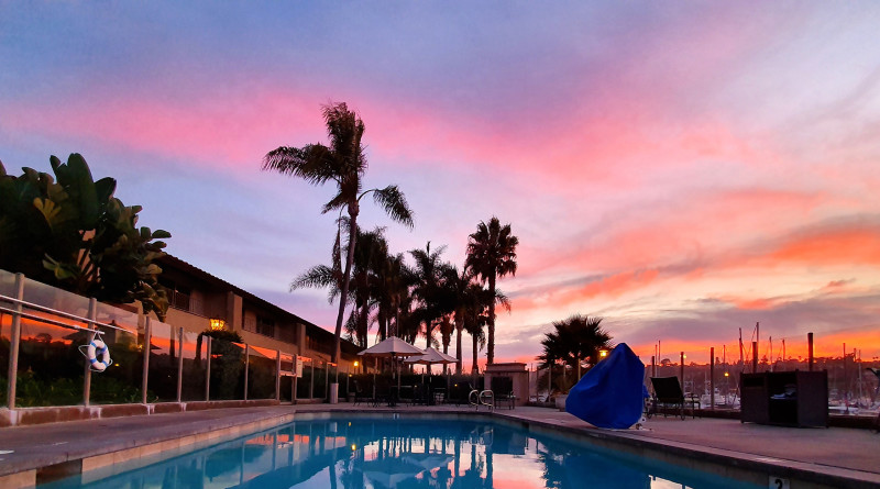 A beautiful shot of a pink California skyline above a public pool in San Diego.