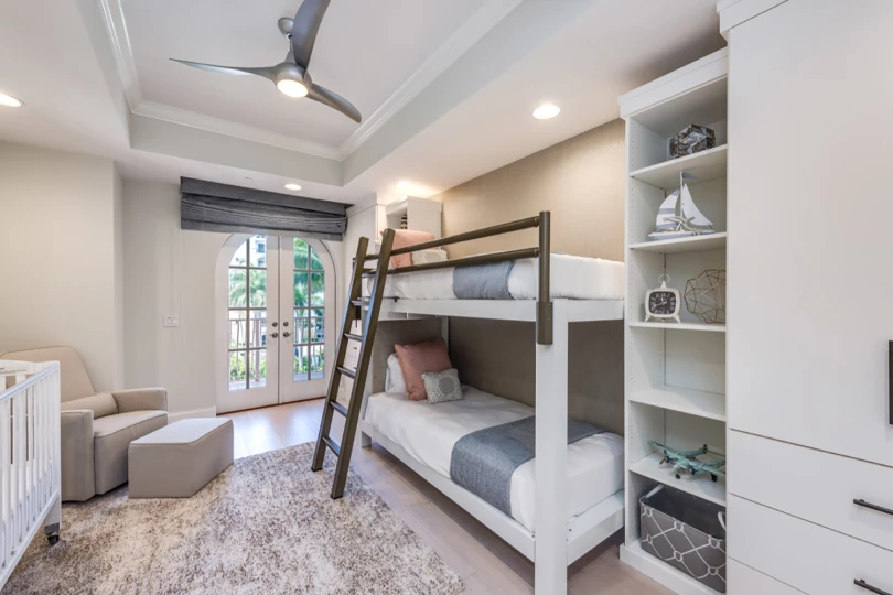 A white Adult Bunk Bed with a light bronze guard rail and ladder seen from the lower left-hand corner of the bed in an upscale bedroom in a Florida vacation home.