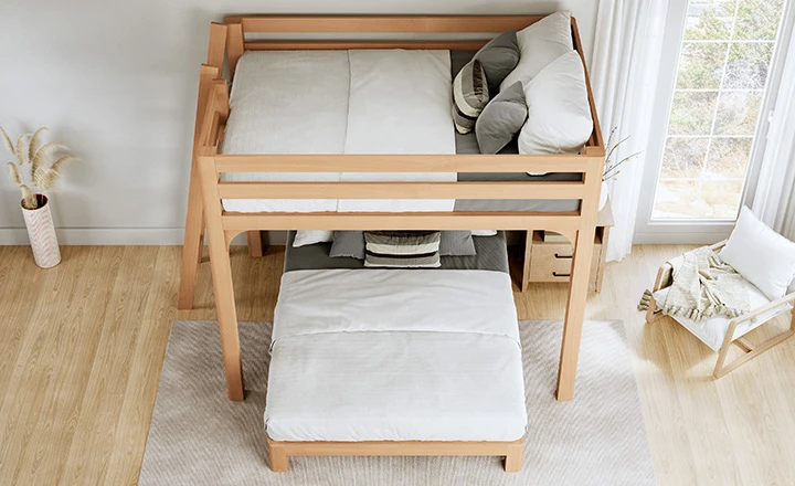 A light colored Queen Over Queen Wood L-Shaped Bunk Bed for Adults in a nice, upscale guest bedroom seen from a high angle at the foot of the bottom bunk.