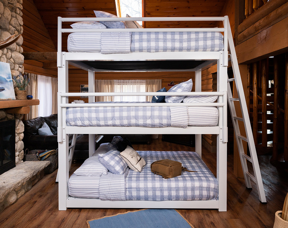 A white Queen Triple Bunk Bed for Adults adorned with blue and white bedding inside of a rustic cabin setting. Seen directly from the side.