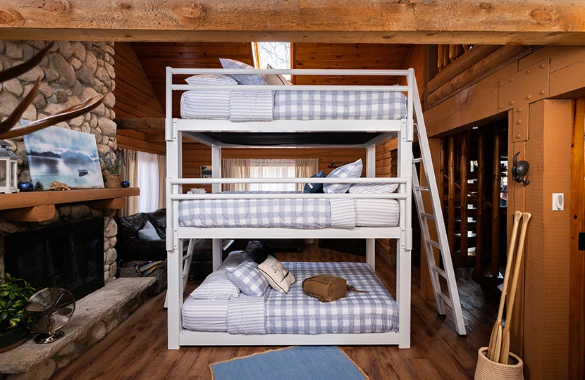 White Triple Bunk Bed for Adults in an upscale cabin setting seen directly from the right-hand side of the bed with the guardrails.