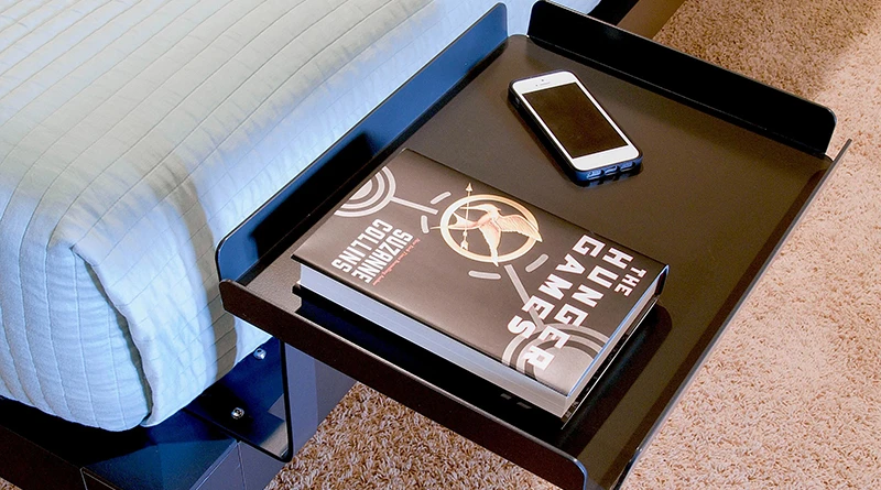 A Tray accessory attached to a charcoal Platform Bed frame with a hardcover book and iPhone lying on it.