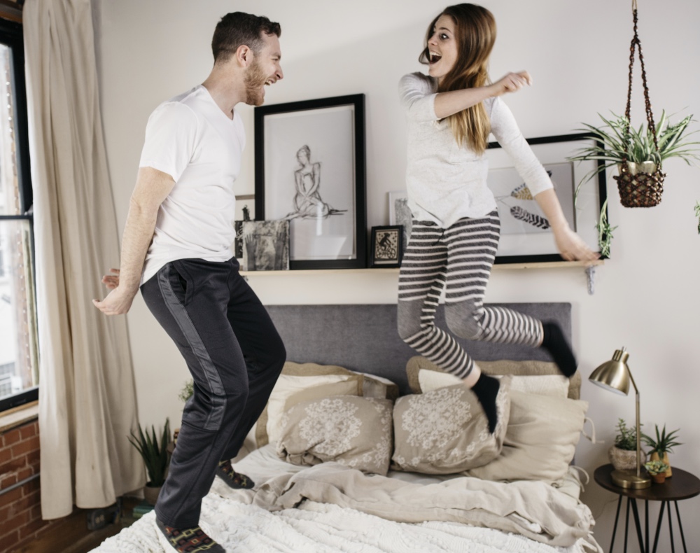 Couple jumping on bed - 1000x790