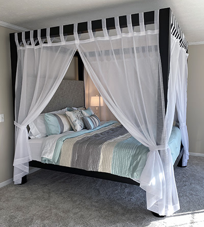 A black king size metal Canopy Bed with white drapes around all four sides.