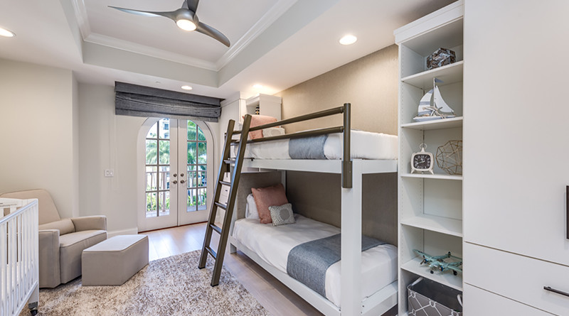 A white Queen Over Queen Adult Bunk Bed with a light bronze ladder and side rail in the guest room of a professionally decorated home in Naples, Florida.