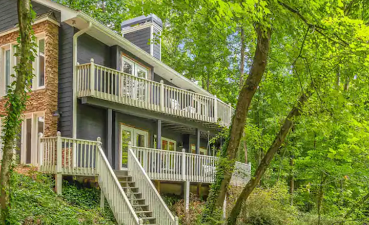 Front view of the Crooked Creek Airbnb property, the property positioned amongst bright green forest.