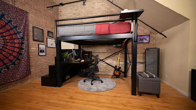 Black queen loft bed for adults with stairs and desk in a nice loft apartment seen from the left-hand side away from the wall at a slight distance.
