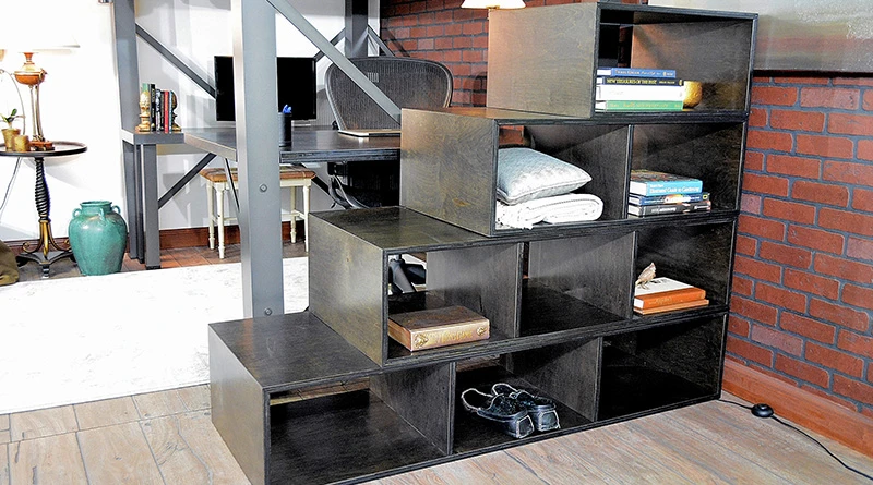 A heritage brown stained wooden staircase positioned horizontally to the foot end of a charcoal colored Queen Size Adult Loft Bed.