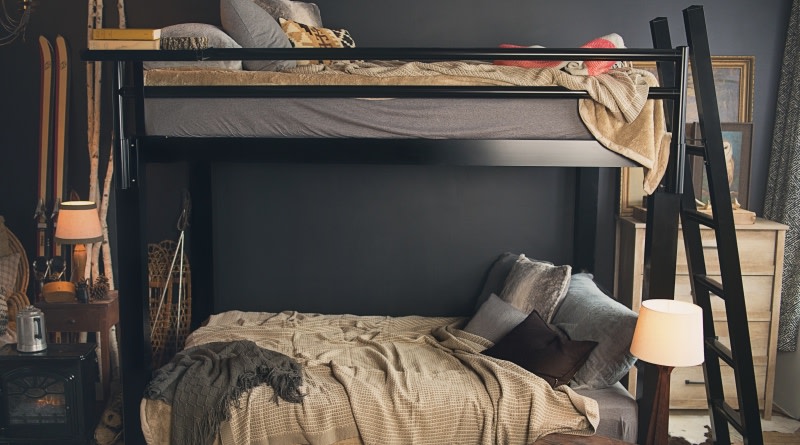 A black Queen Over Queen Adult Bunk Bed sits in the bedroom of a ski resort cabin.