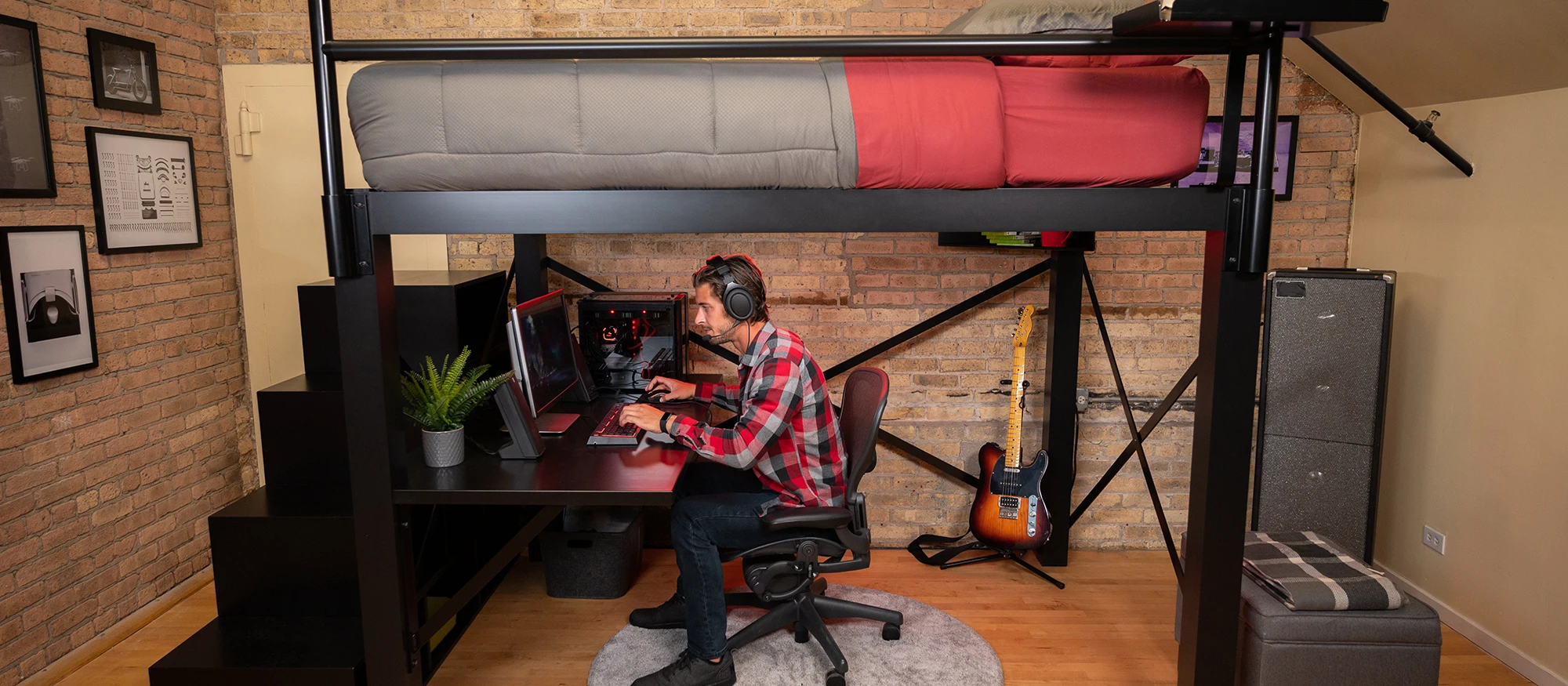 Young adult man sitting at the attached desk underneath his Queen Loft Bed for Adults playing video games on his PC.