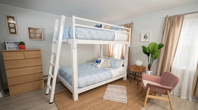 White Queen Over Queen Adult Bunk Bed in a beach house bedroom seen from the left-hand side of the bed at a slight angle toward the foot of the bed.