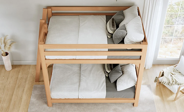 Light colored queen over queen size Wood Bunk Bed for Adults in a nice, airy, upscale guest room. Has white and light gray bedding on it. Seen from the left-hand side of the bed at a high angle overlooking the bed frame.