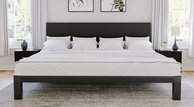 Charcoal Alaskan King size metal Platform Bed in an upscale but modest master bedroom with white walls and bright decor. Charcoal colored fabric headboard. All white bedding and pillows. Seen directly from the foot of the bed.