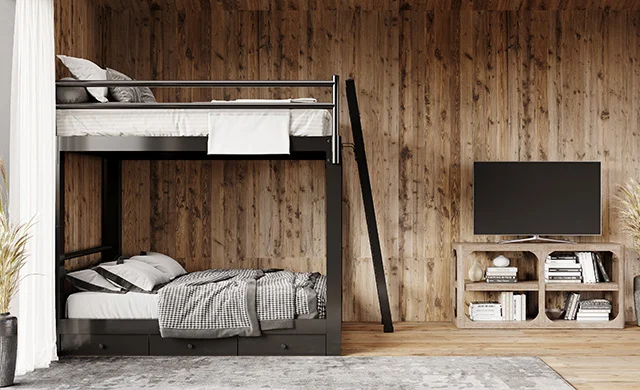 A black Queen Over Queen Adult Bunk Bed in a rustic, sparsely decorated cabin. Seen from the right side from a distance.