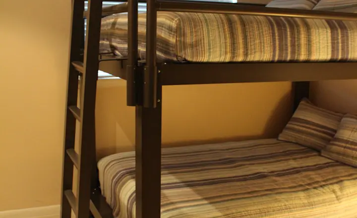 Dressed Black Queen Over Queen Adult Bunk Bed in a Basement