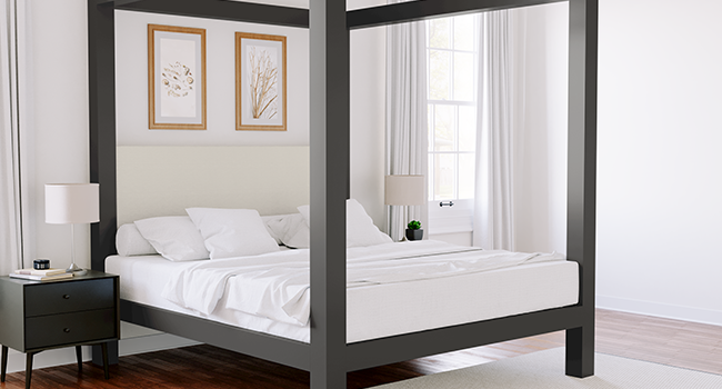 Charcoal King size metal canopy bed with an Ivory headboard in a nice upscale room. Seen from the lower right-hand corner.