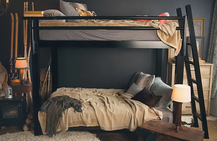 A black Adult Bunk Bed in a ski cabin bedroom seen directly from the left-hand side of the bed.