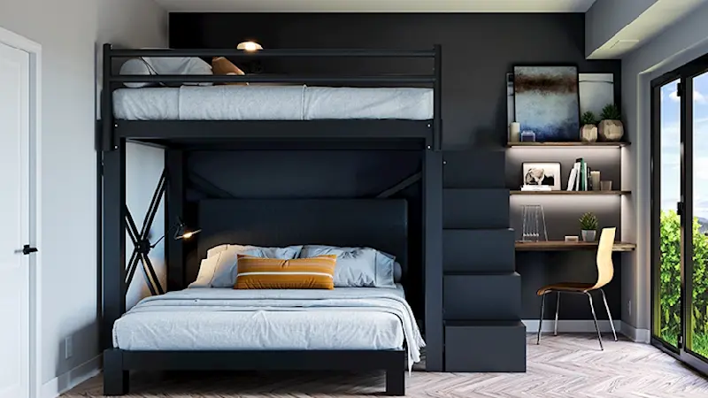 A black Full Over Queen size L-Shaped Bunk Bed for adults with a matching wooden staircase in a nice, upscale guest room. Seen from directly at the foot of the bottom bunk, with the top bunk turned to see the right-hand side of the bed with the guardrail.